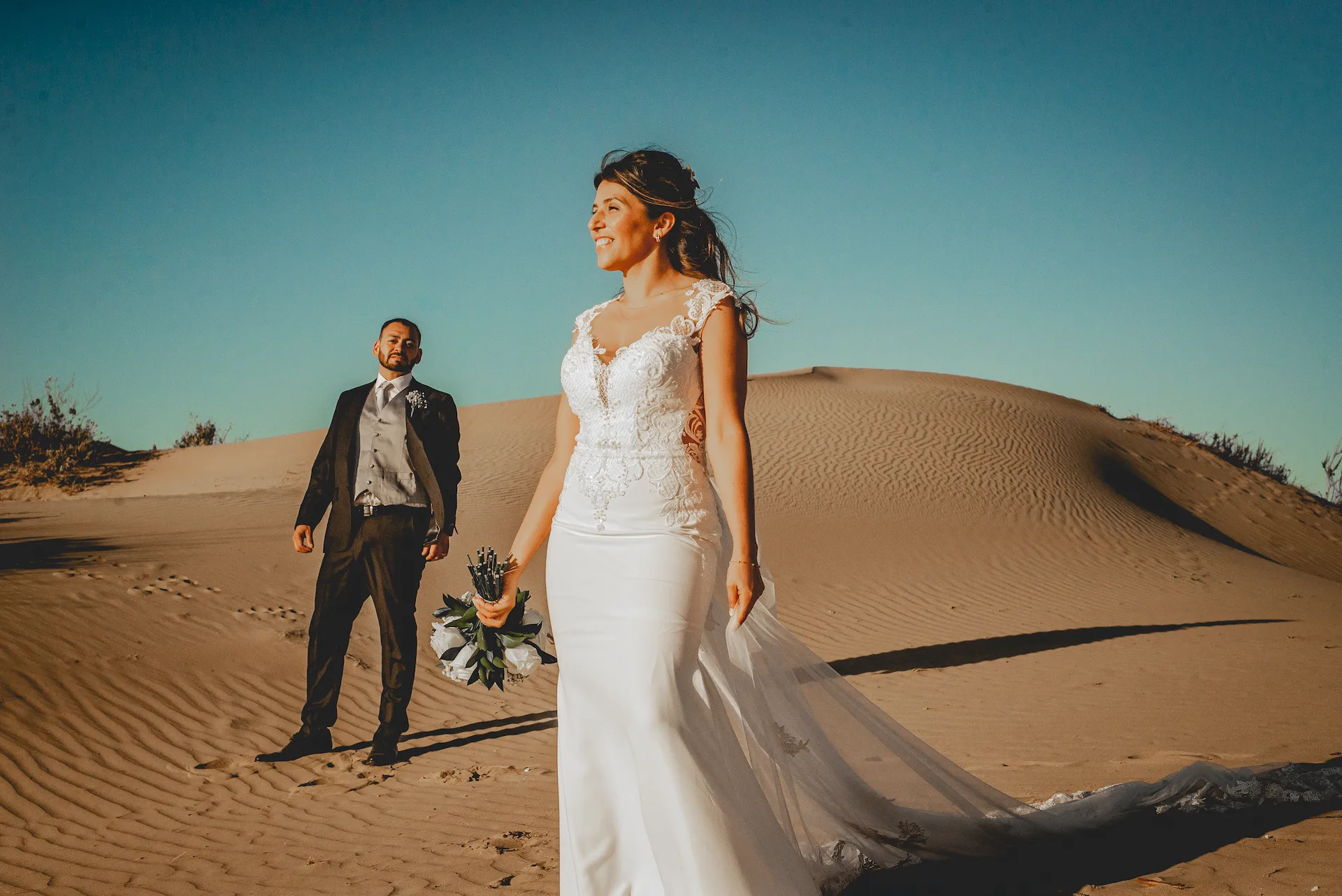 Novios en sesión fotográfica de boda con fondo montañoso en la playa de La Serena.